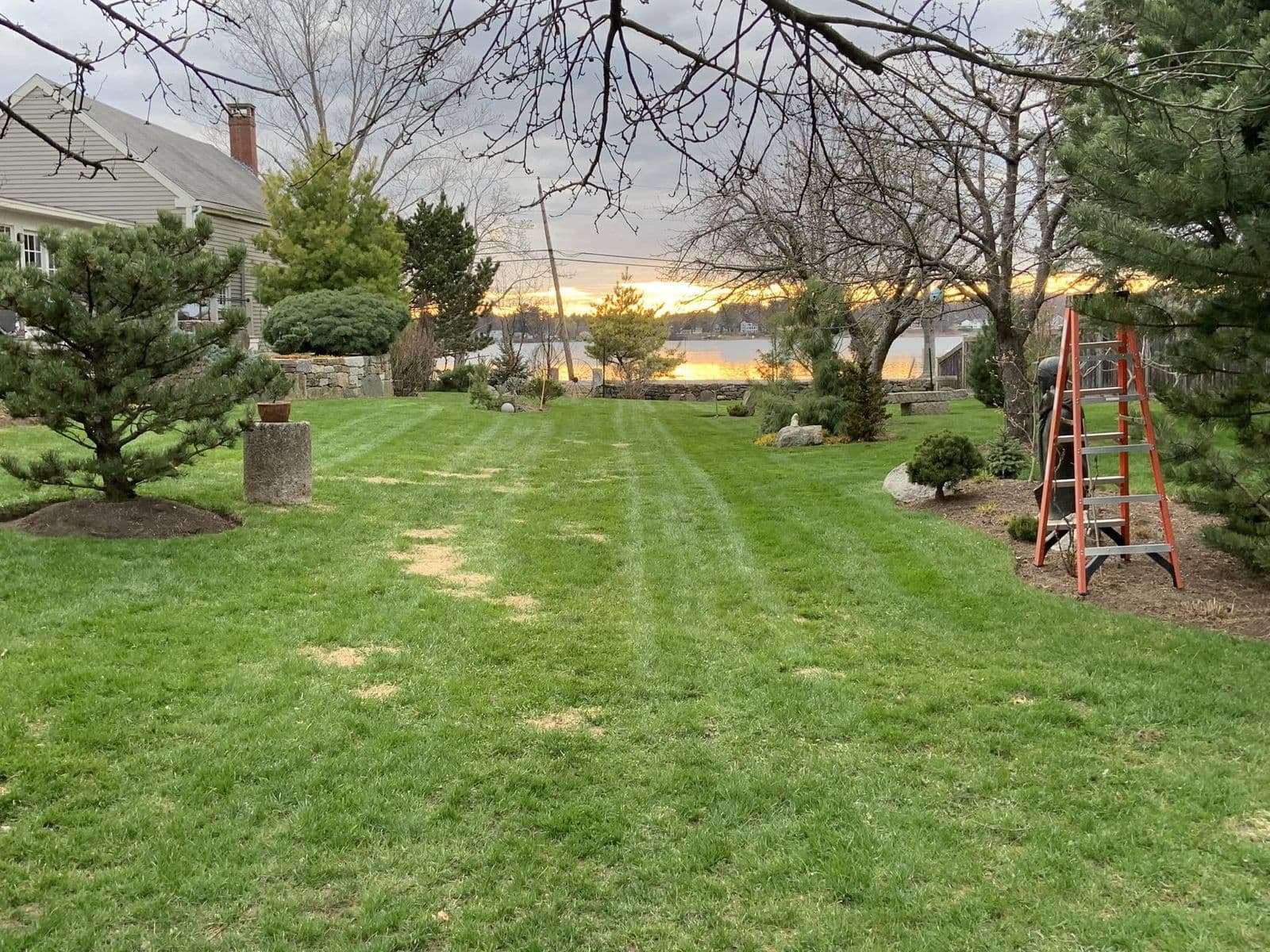 Freshly mowed lawn with mowing stripes overlooking water at sunset